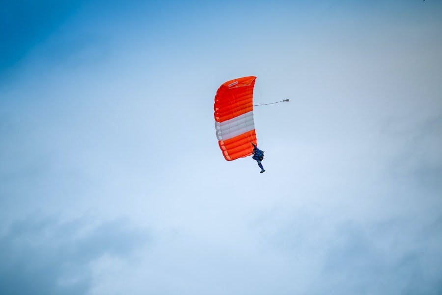 skydiver with orange and white parachute
