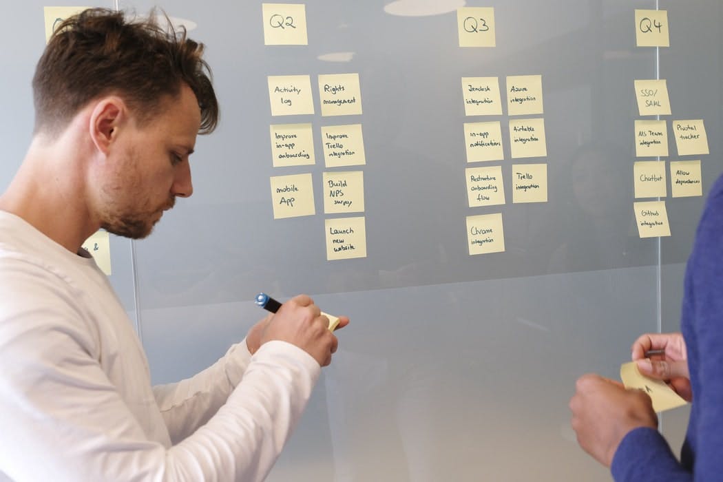 teammates planning quarterly product goals with sticky notes on a whiteboard 